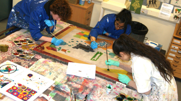 3 art students painting on a canvas