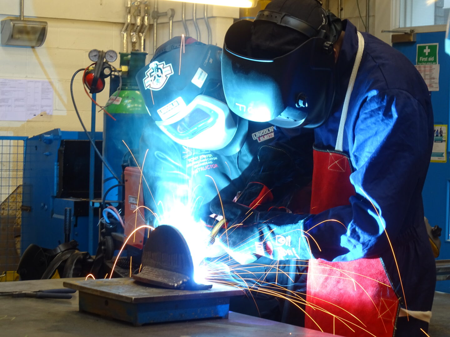 2 welding students working on a welding project as sparks fly