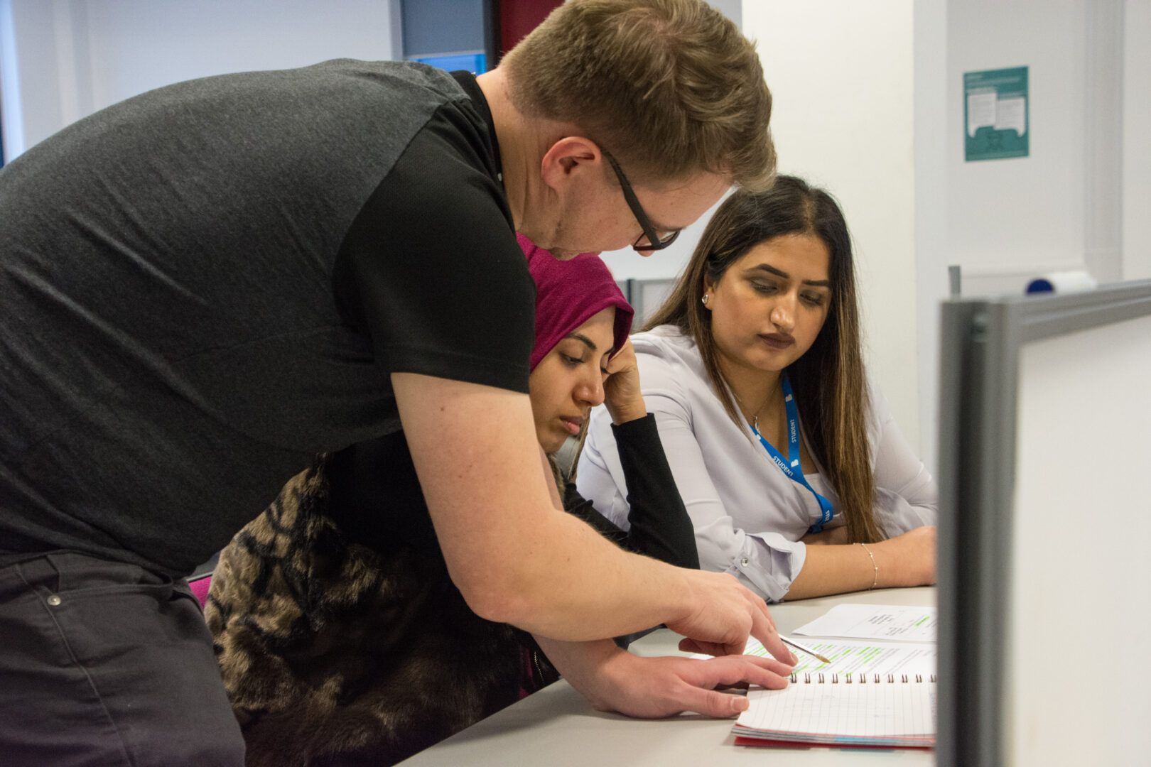 staff helping 2 students with their work