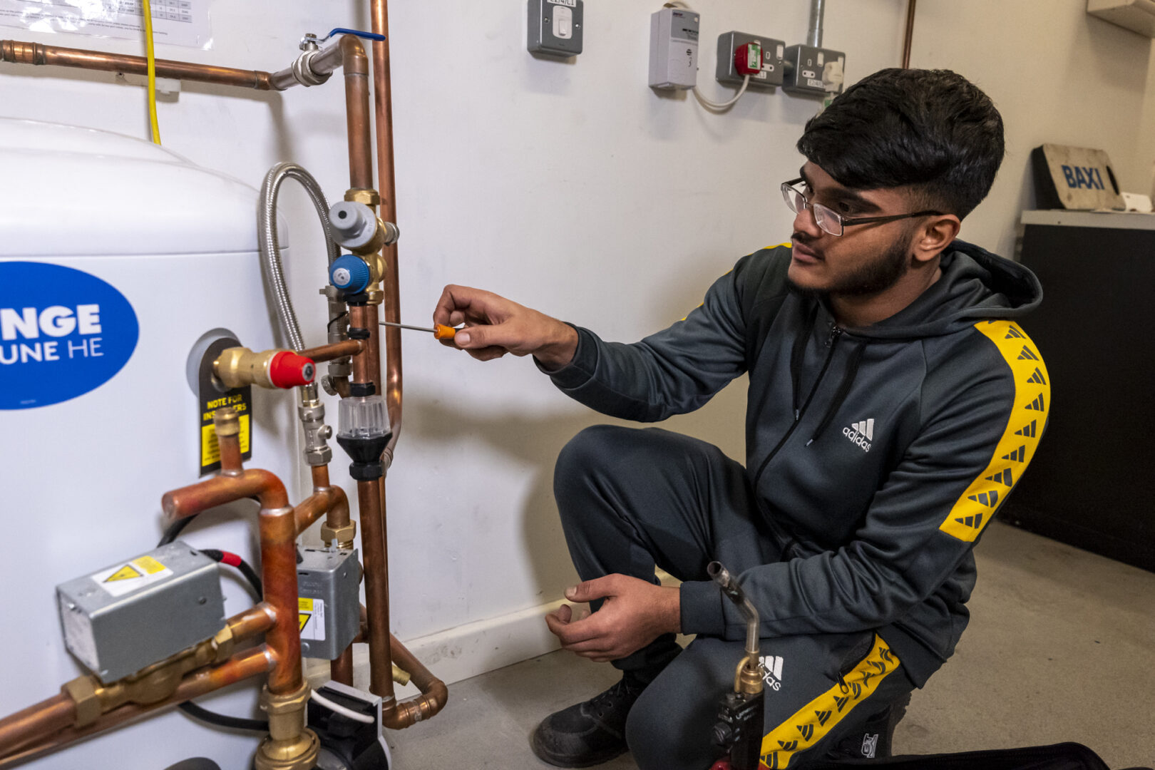 a plumbing student knelt working on pipes