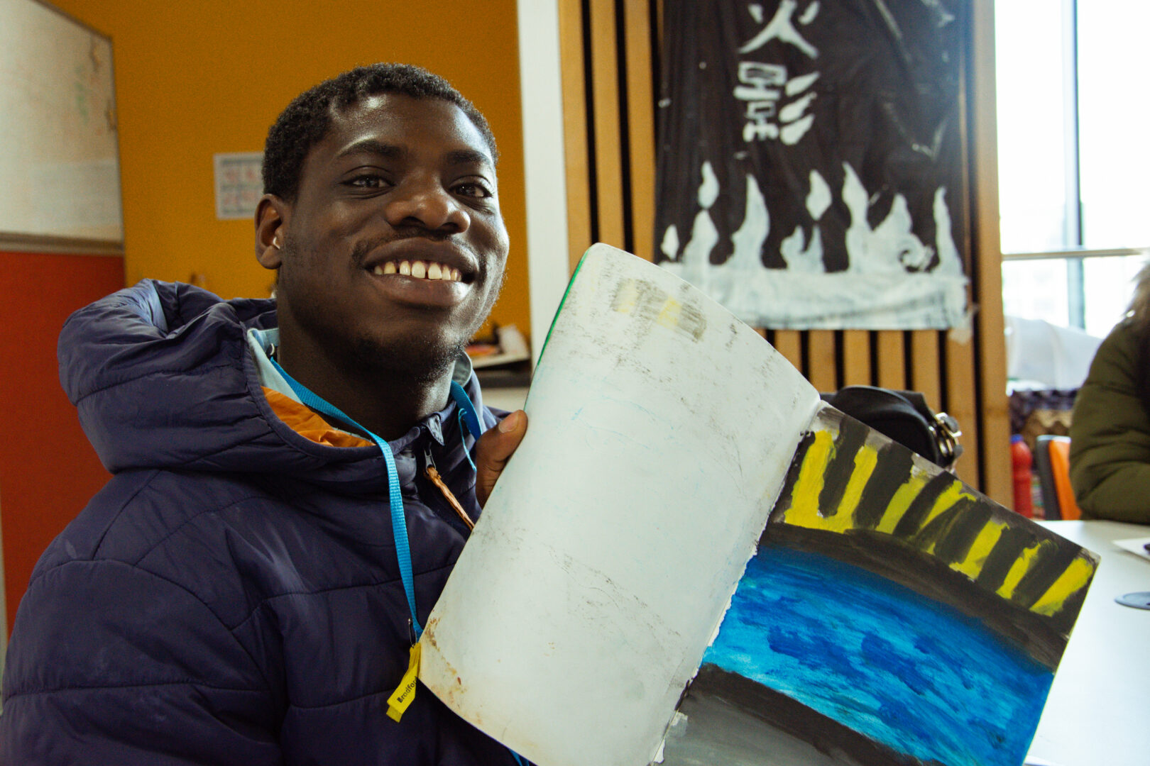 smiling student holding work book full of artwork