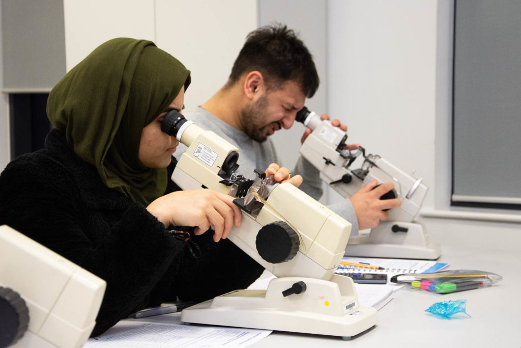 ophthalmic dispensing students looking through optician equipment