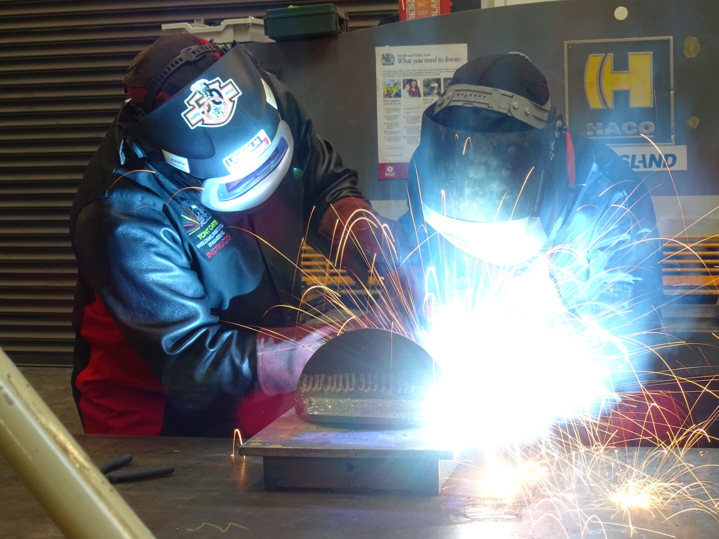 welding students welding a piece of metal as sparks fly from it