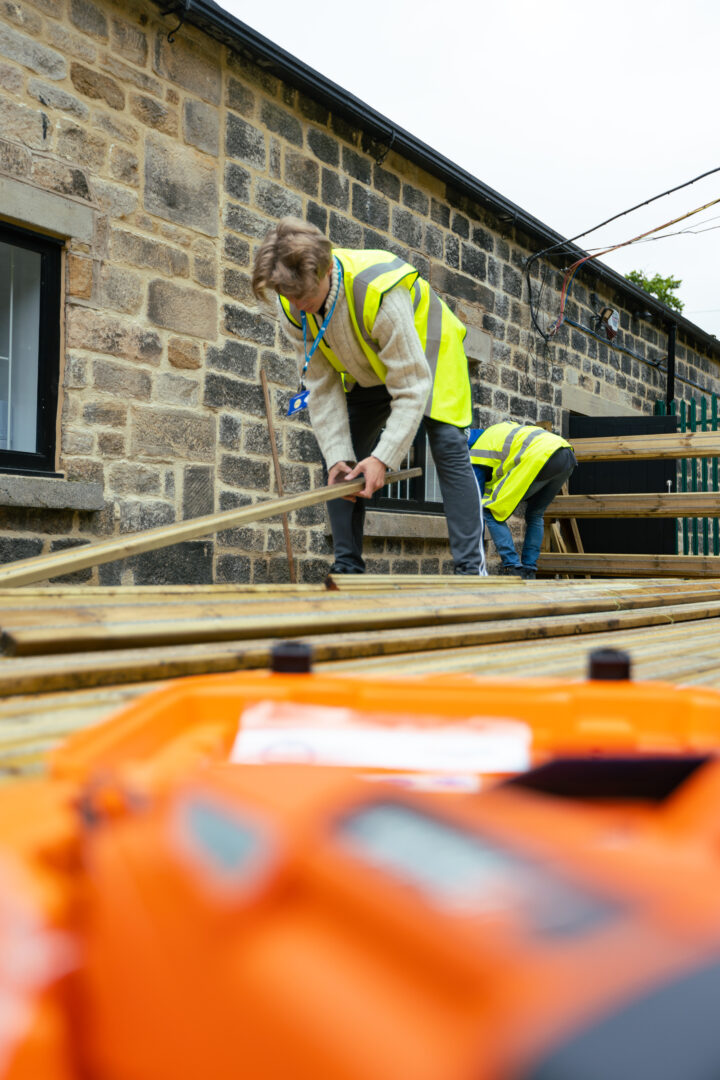 construction student placing a wood on decking on a construction site