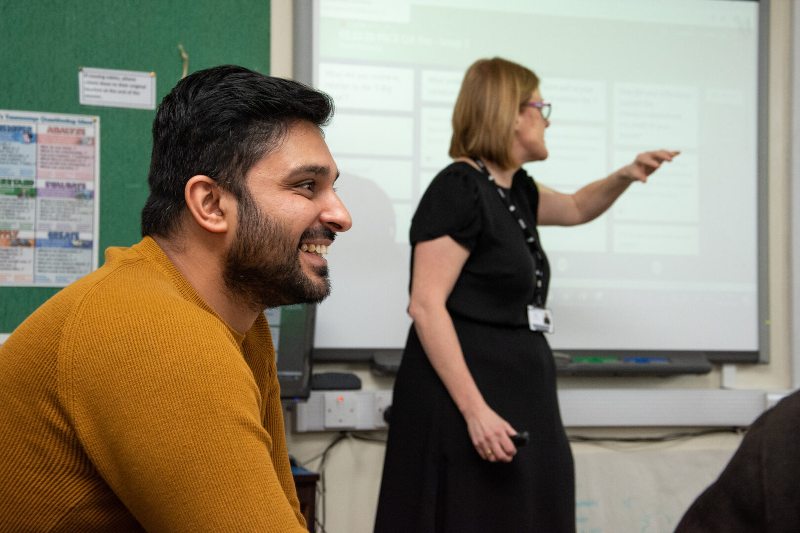 a teacher is stood in a classroom with a student