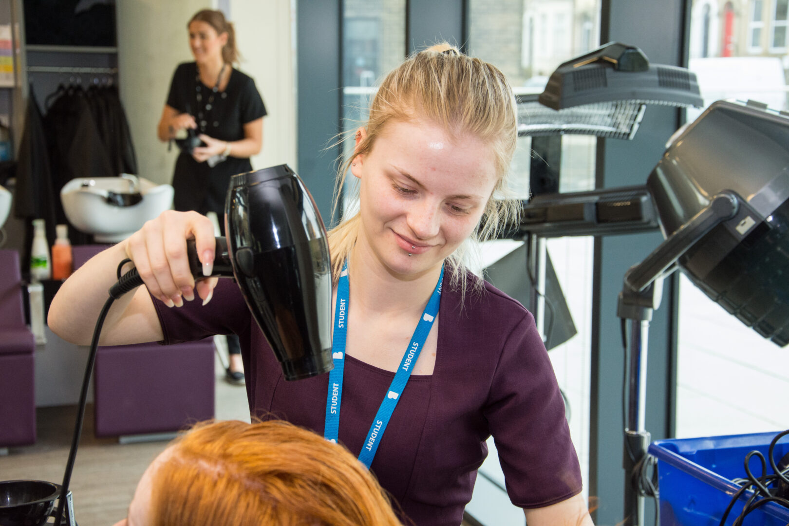 hairdressing student drying the hair of a hair model in the hairdressing studio