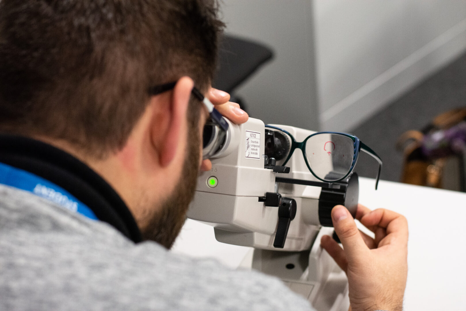 ophthalmic student assessing the strength of a pair of prescription glasses