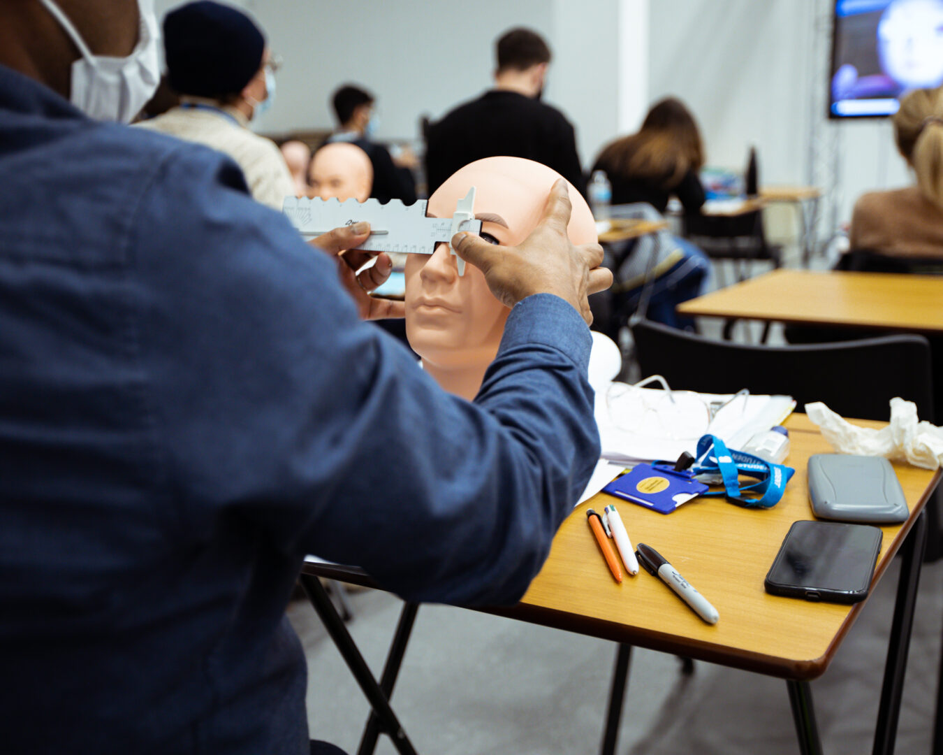 ophthalmic student working on a mannequin head measuring the distance between the eyes