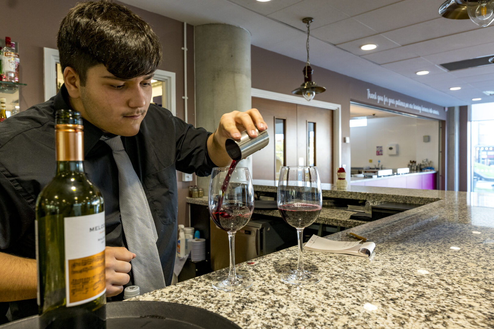 catering and hospitality student measuring portions of wine