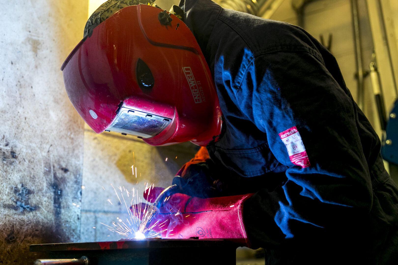 welding student welding a piece of metal as sparks fly
