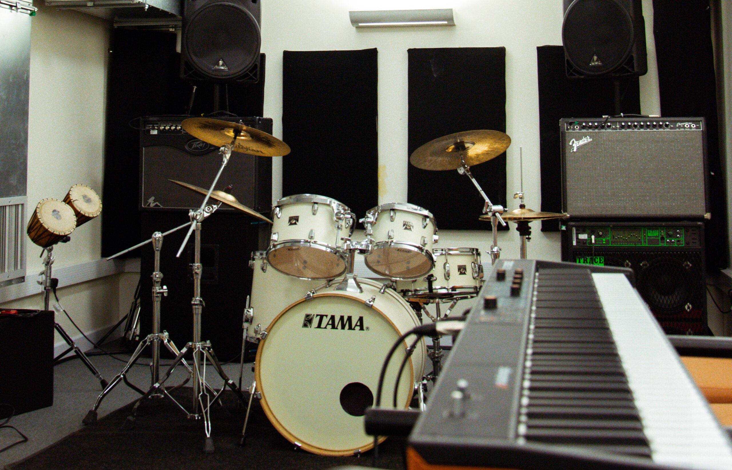 a music studio showing a drumkit and keyboard and speakers