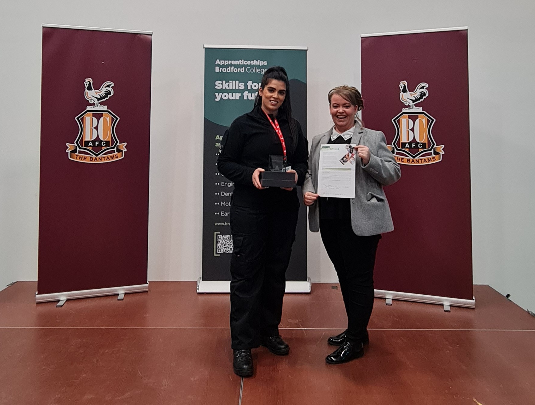 one person holding an award and another person holding a certificate