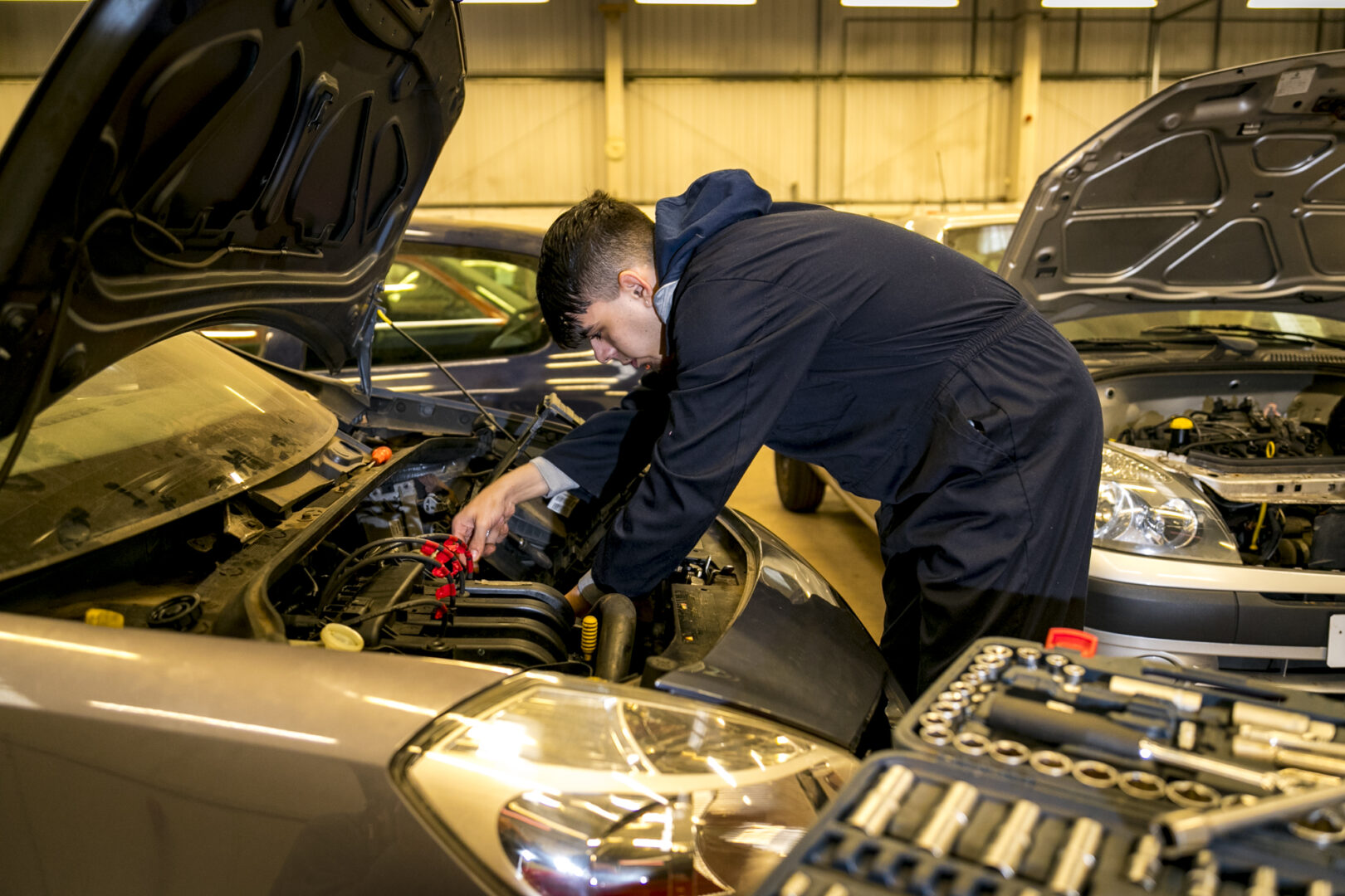 a motor vehicle student working under the bonnet of a vehicle
