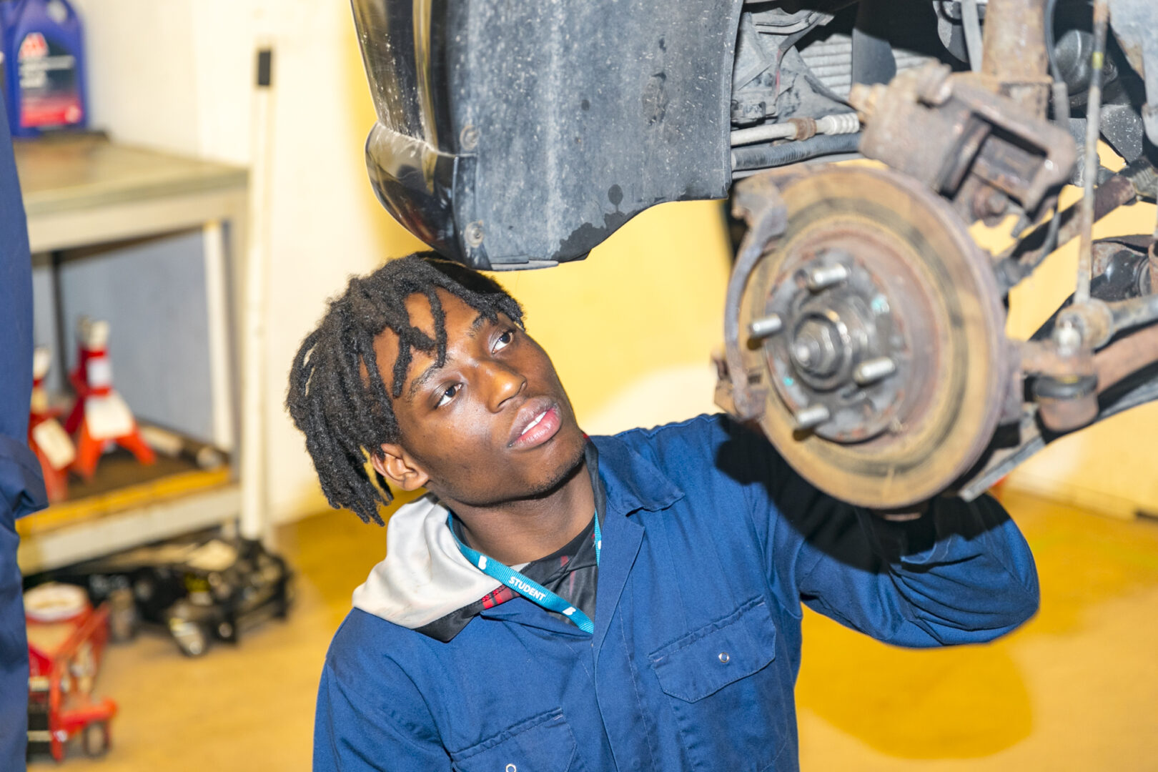 a motor vehicle student stood inspecting the bottom of a vehicle