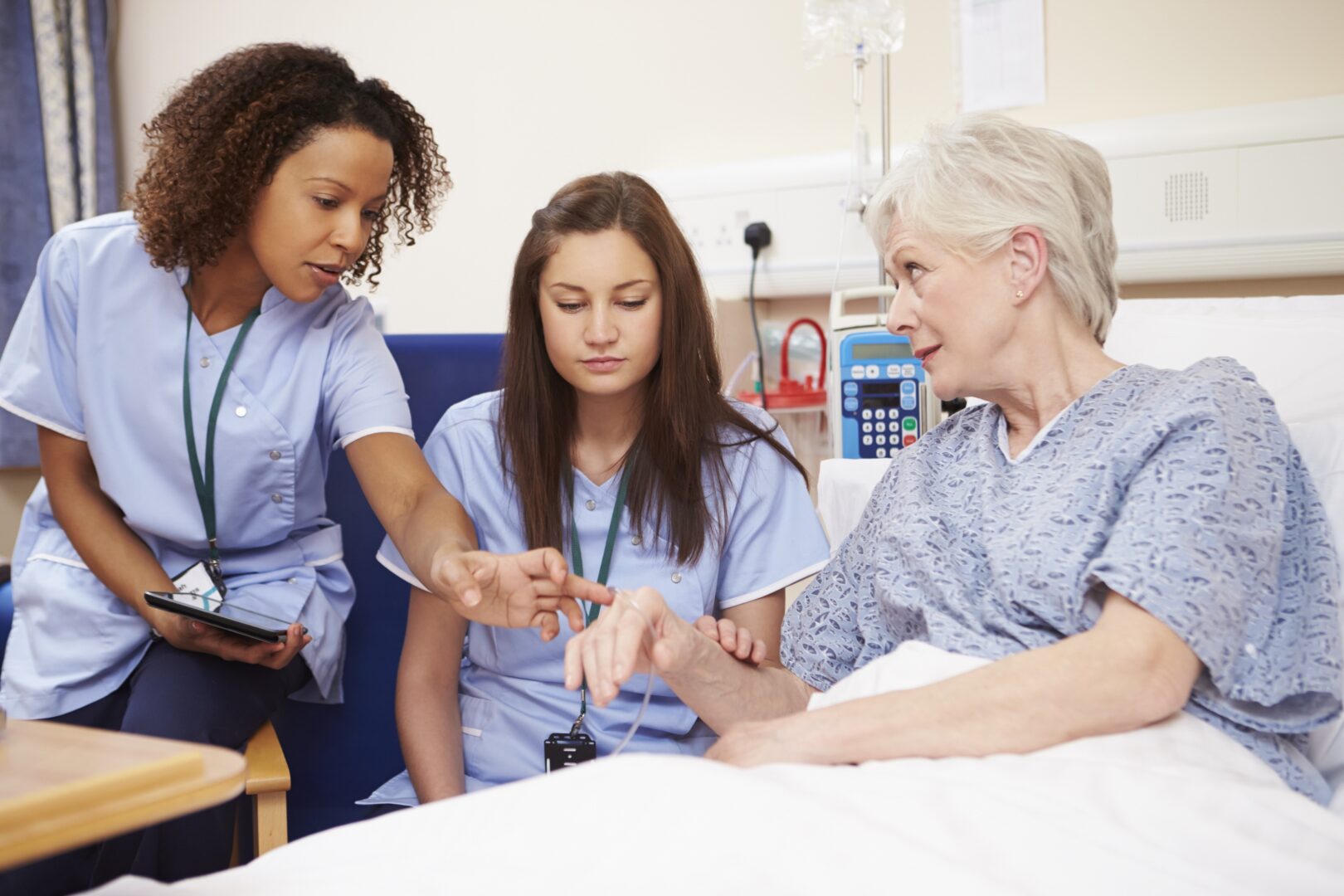 two nurses helping an elderly patient