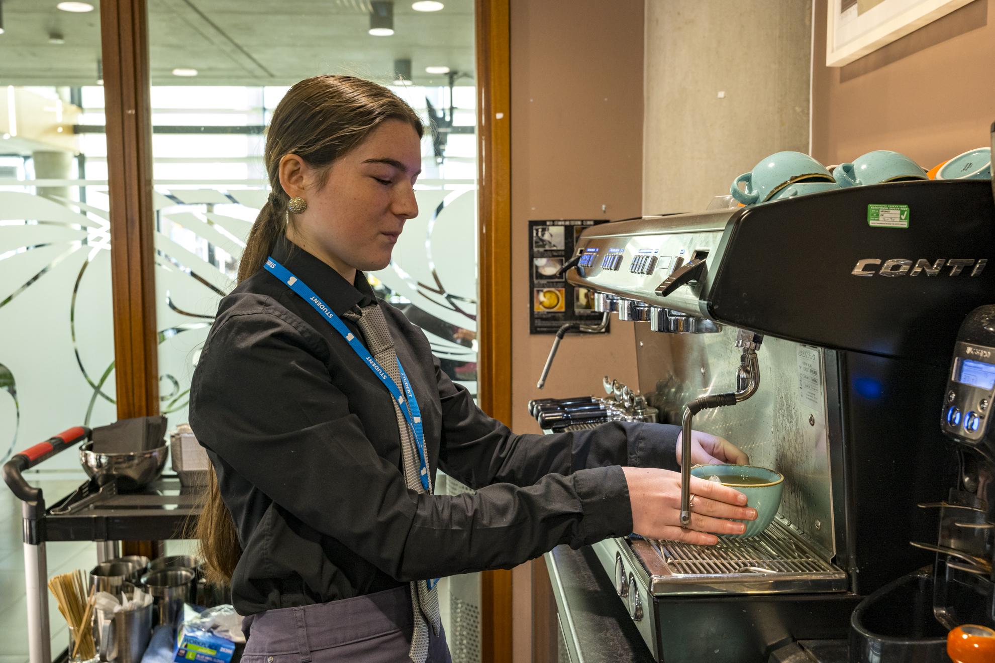 a student stood making a coffee at the barista machine in the grove cafe