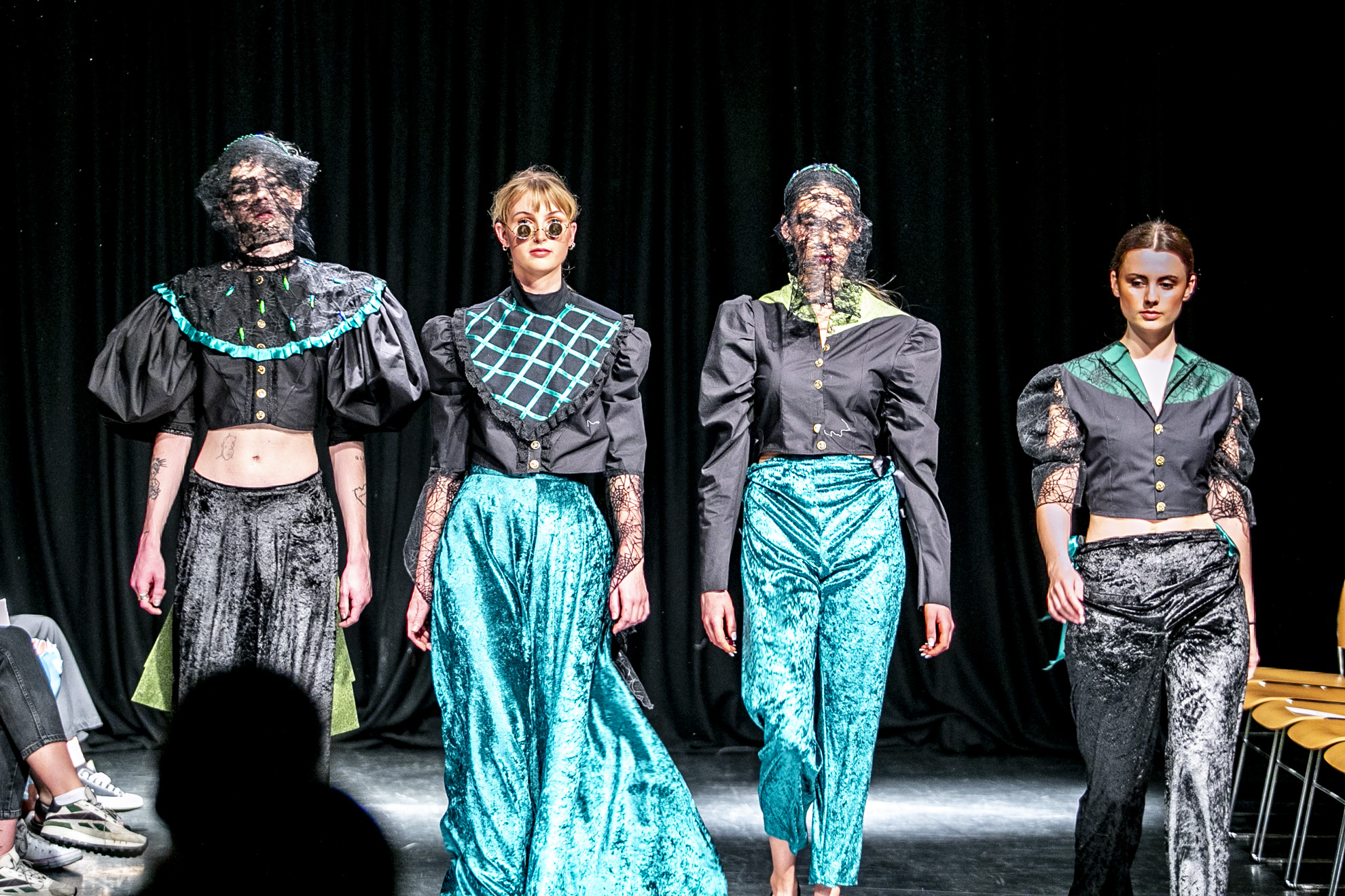 four fashion students in costume walking down the runway
