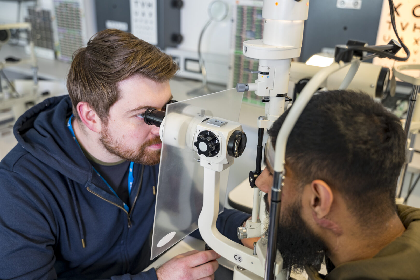 an ophthalmic dispensing student using ophthalmic equipment to look at the eyes of a patient