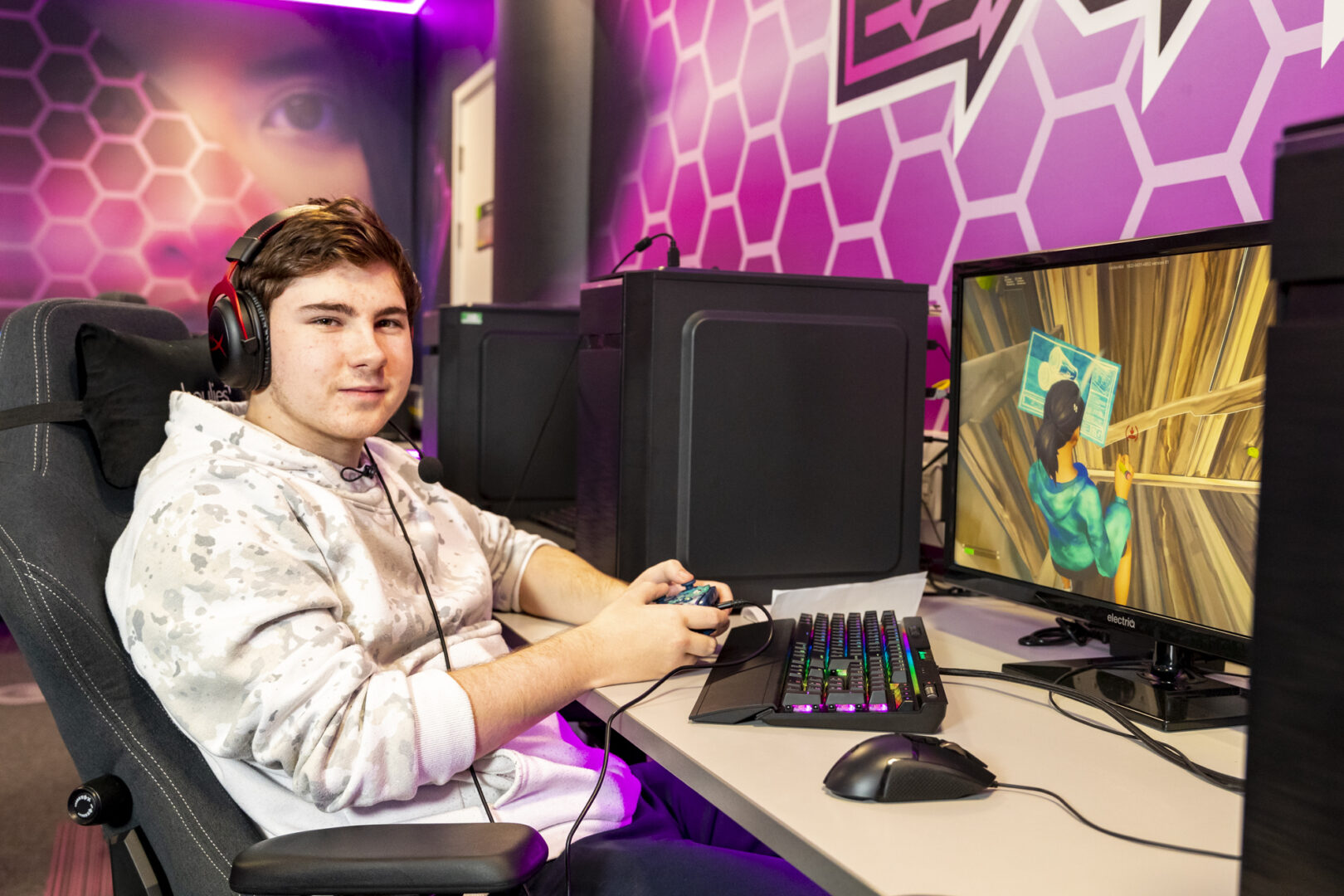 an esports student wearing headphones sat at a monitor