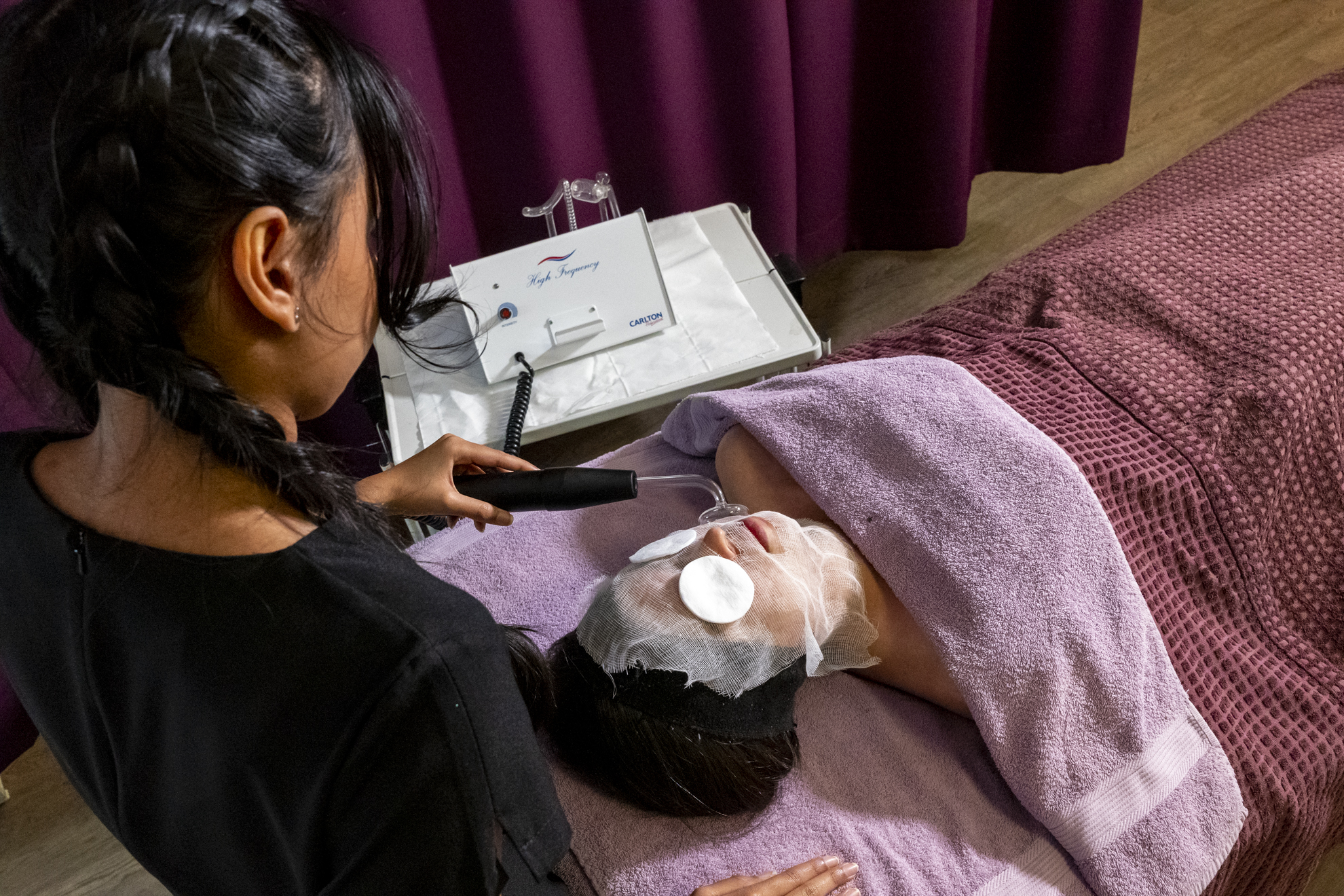 a beauty therapy student performing a facial treatment on a patient