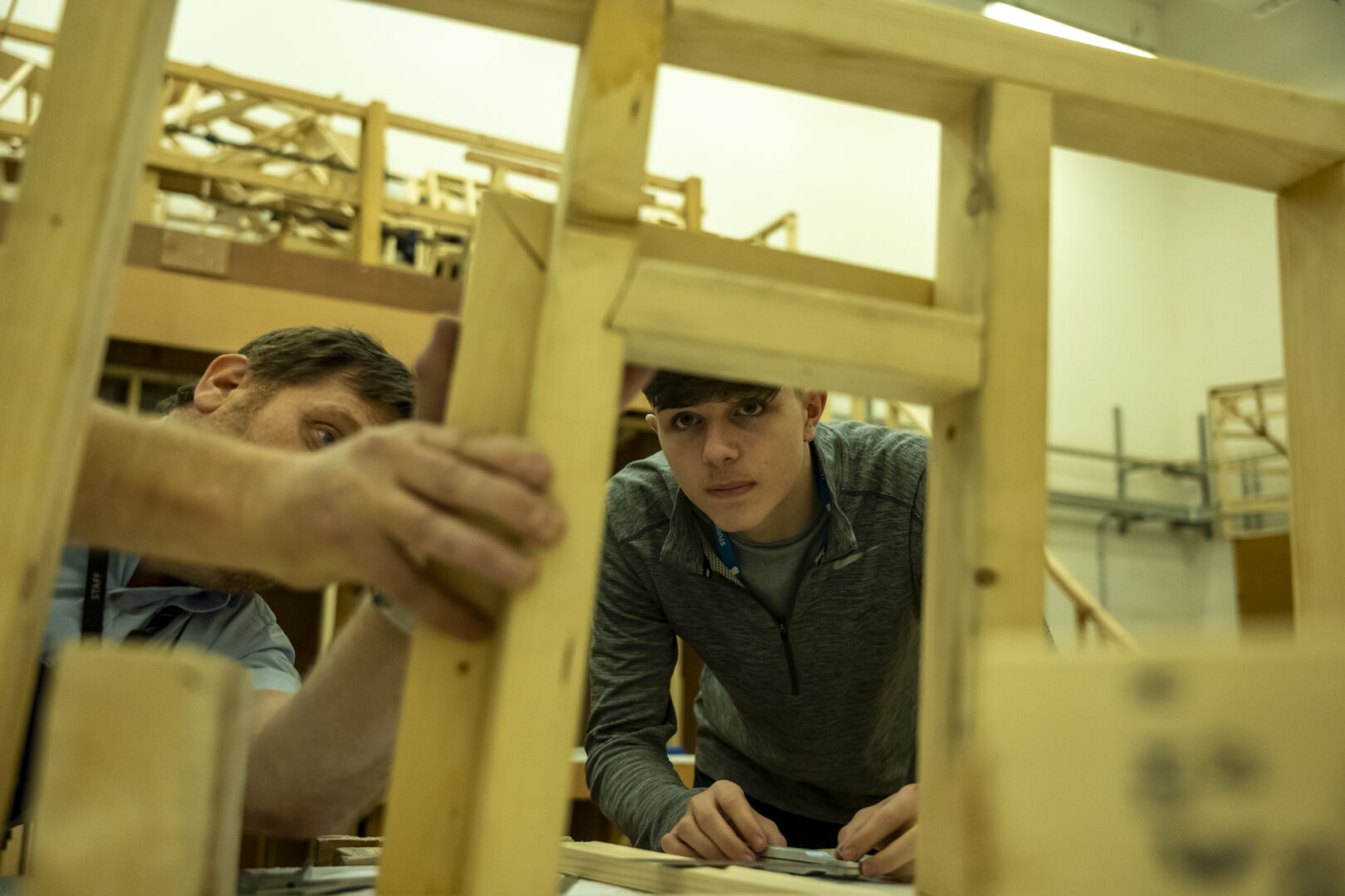 a construction, carpentry and joinery student looking at woodwork with a subject tutor