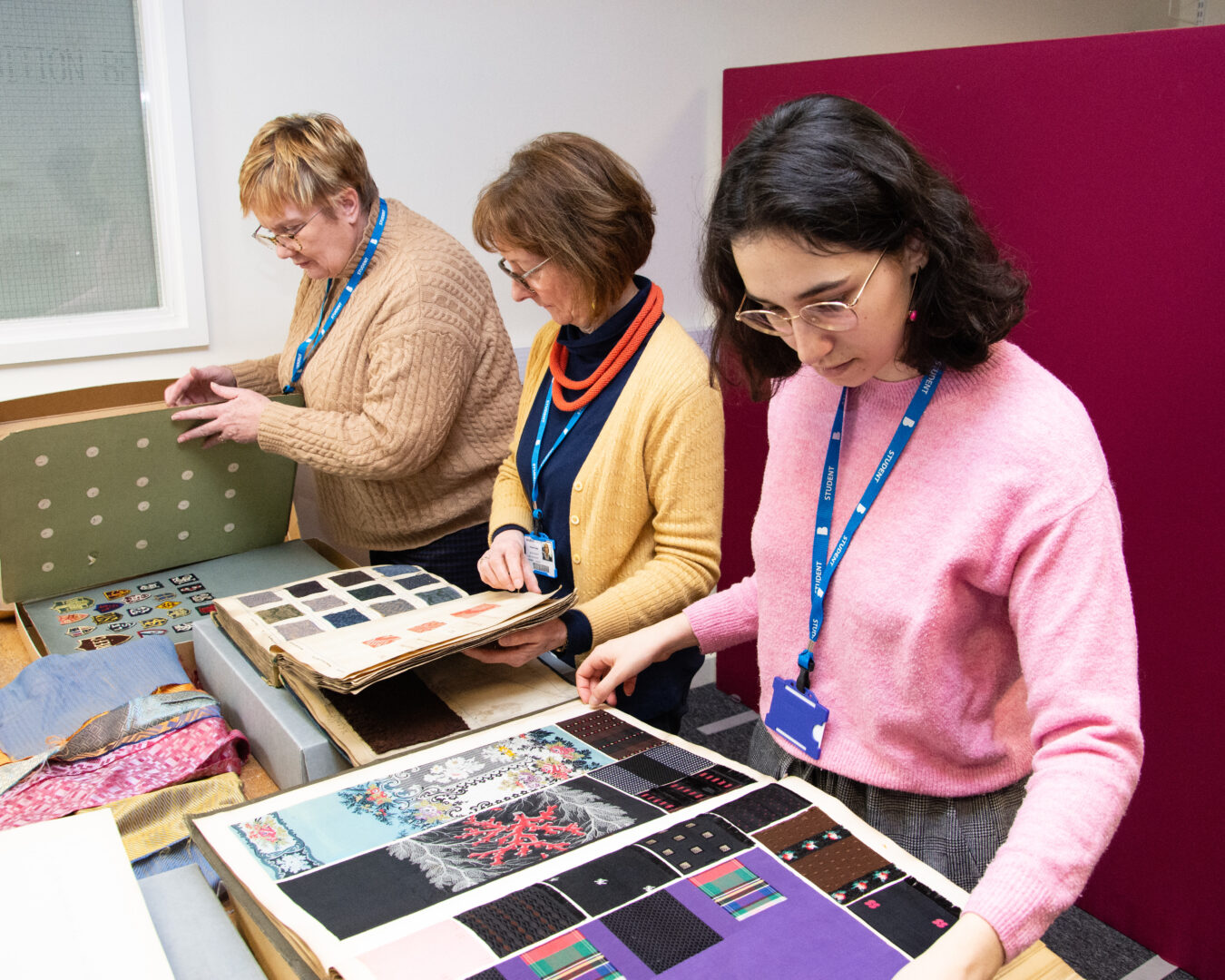 a group of textiles students looking through a book of fabrics