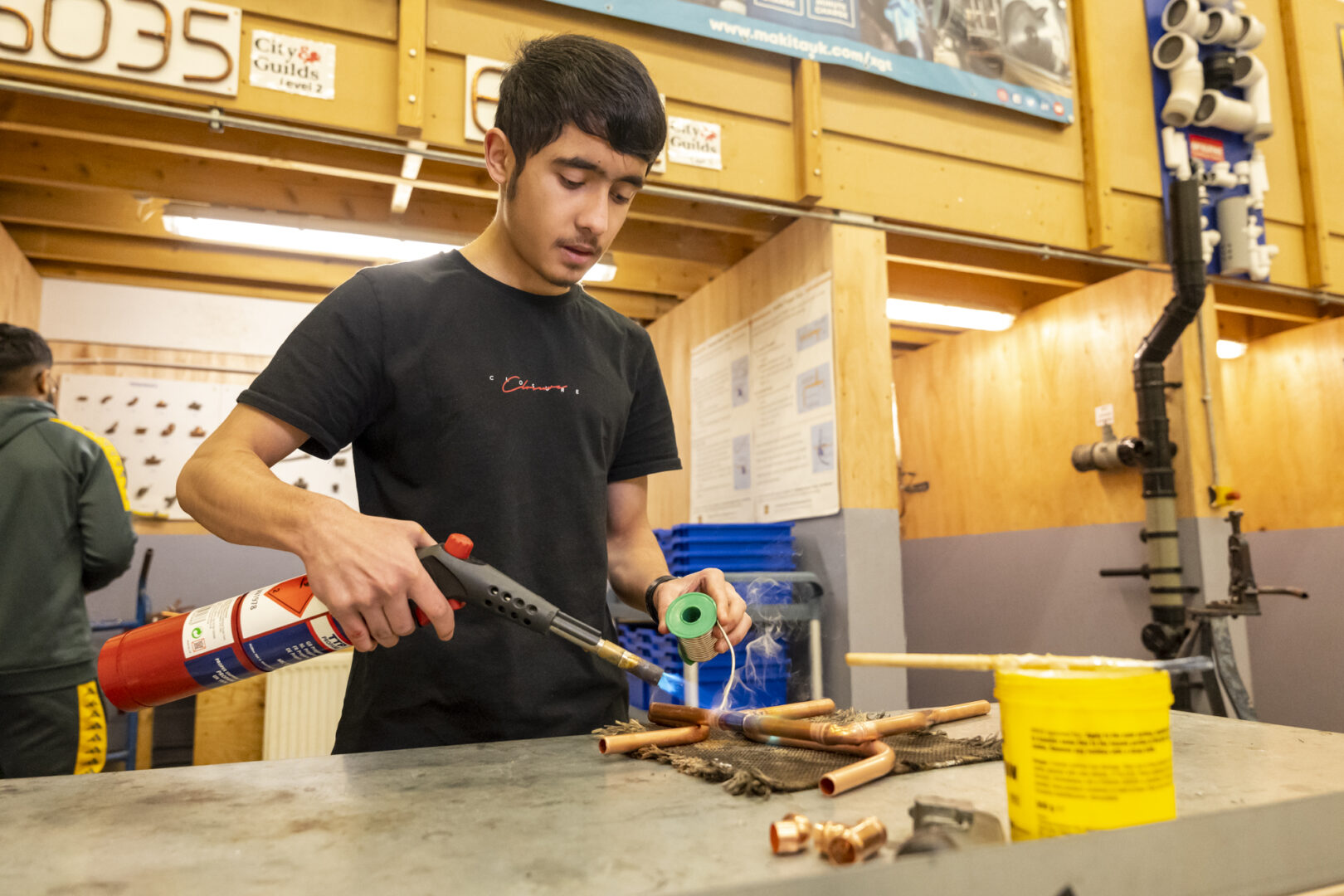 plumbing student using equipment to bend and joint copper pipes