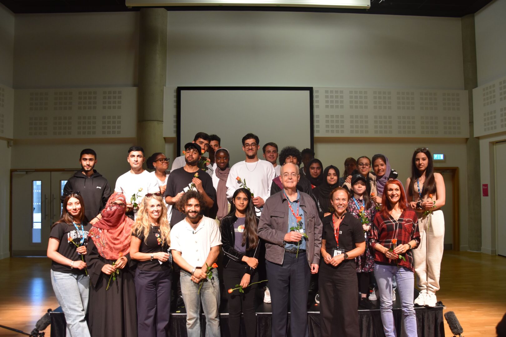 a group of esol students stood on stage after their performance of "because"