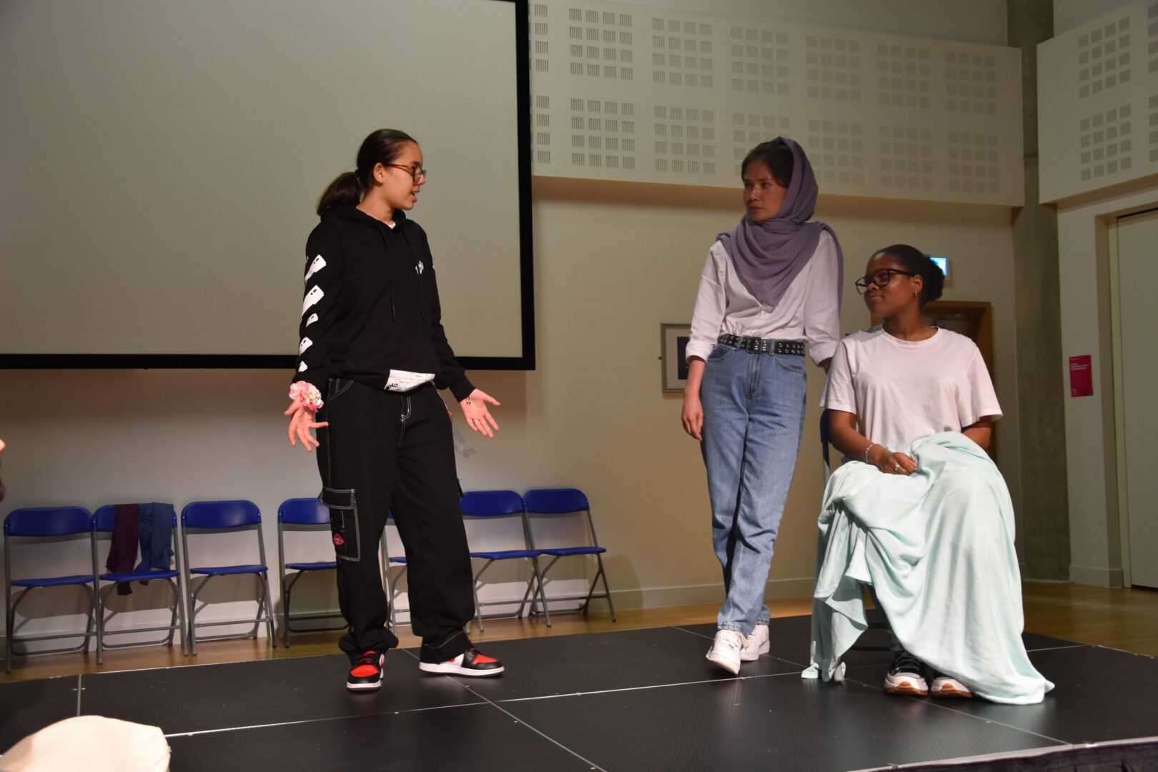 a group of 3 esol students stood on stage performing