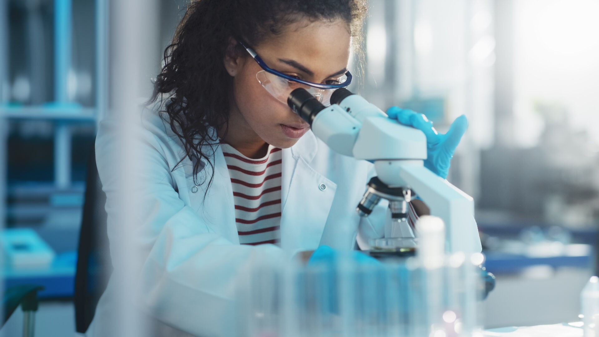 a person looking through a microscope in a labratory