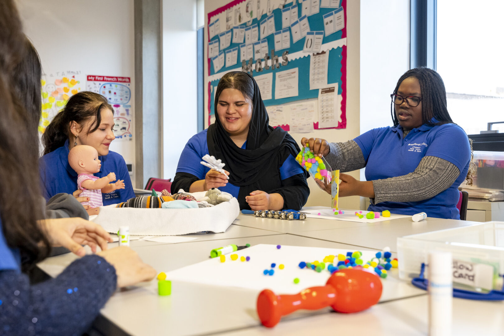 t level education and childcare students sat at a desk with children's educational toys displayed