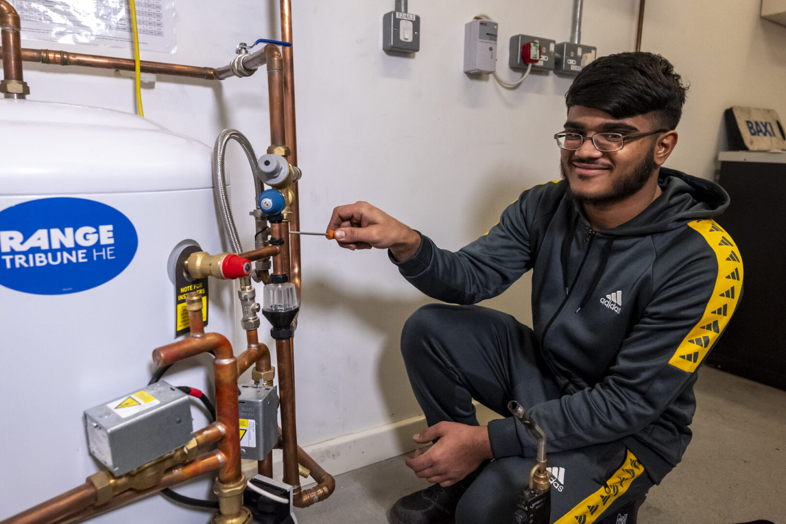 plumbing student concentrating as he holds a screwdriver and fixes pipes