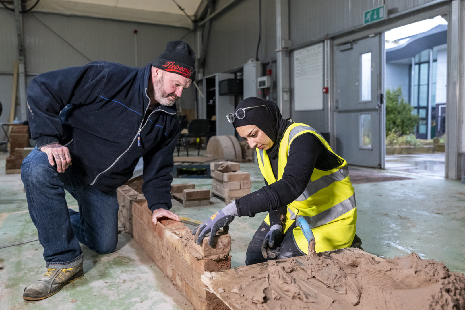 a bricklaying student wearing a hi-vis jacket laying bricks