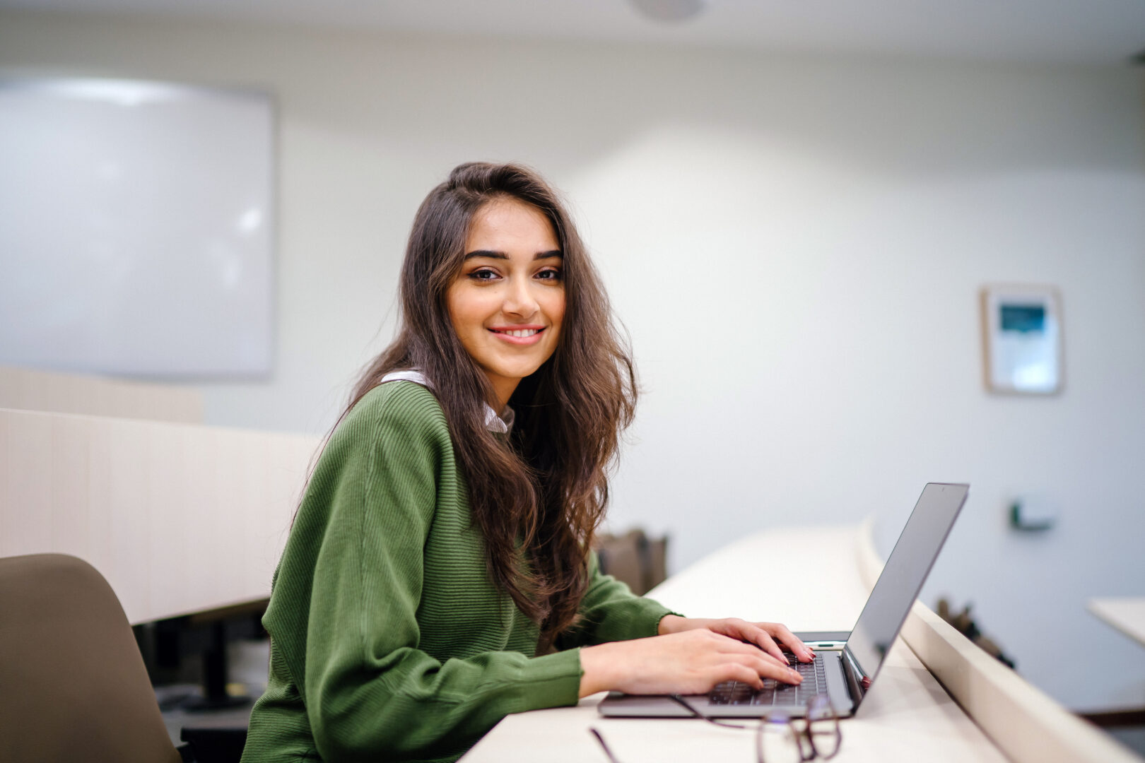 a management and administration student sat at a desk working on a laptop