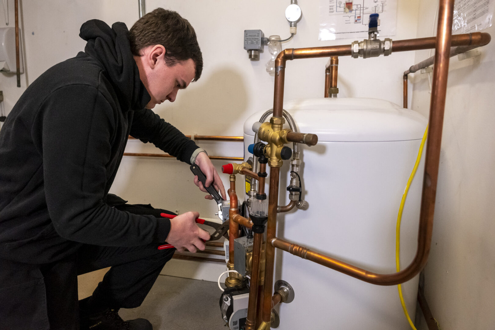 a plumbing student using tools on replica pipes