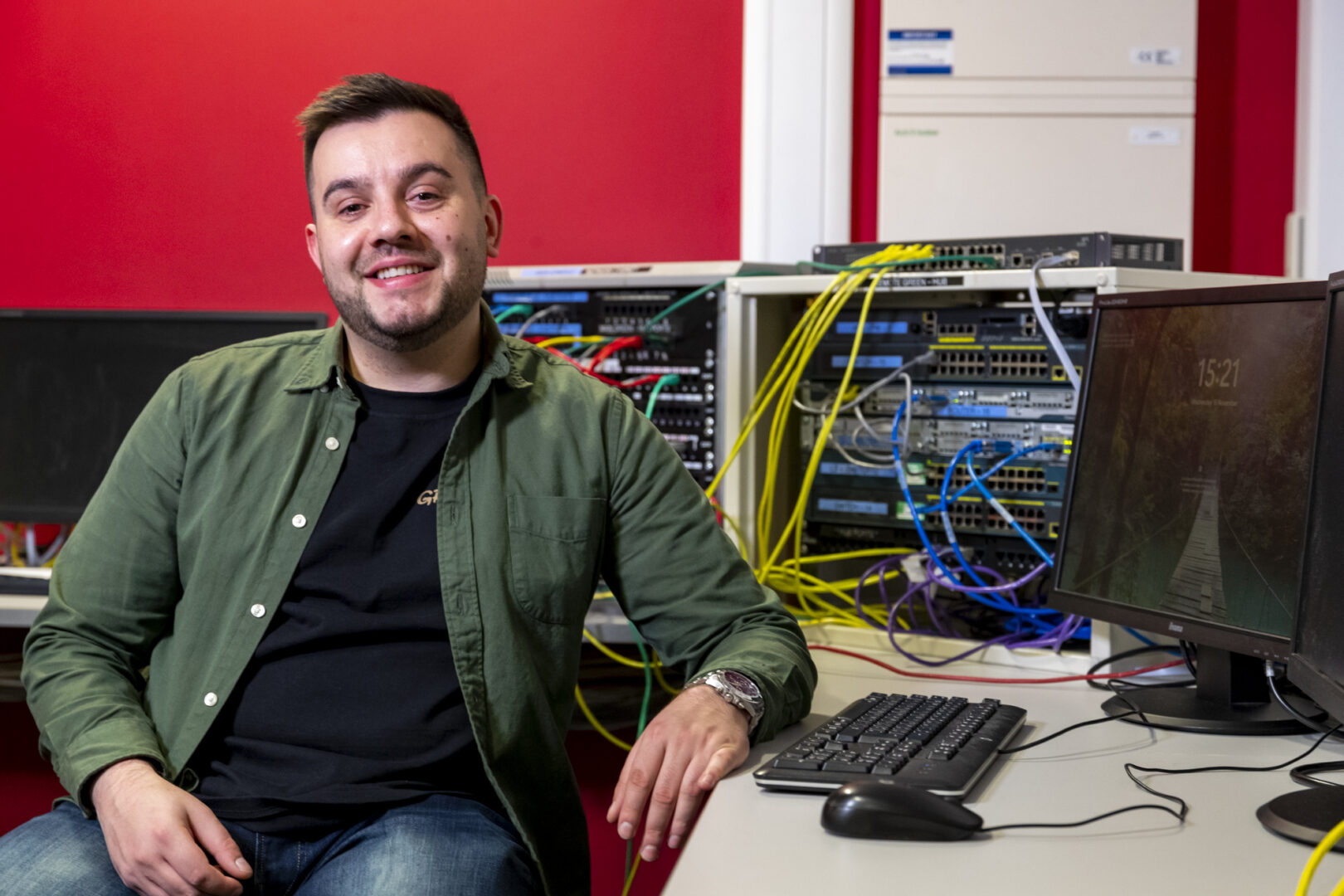 a computing student sits at a computer smiling at the camera