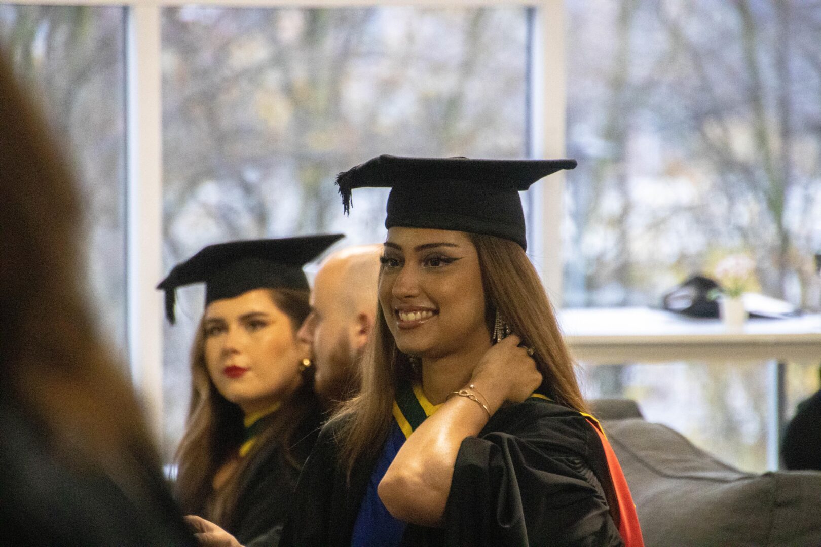 a smiling graduate wearing a cap and gown
