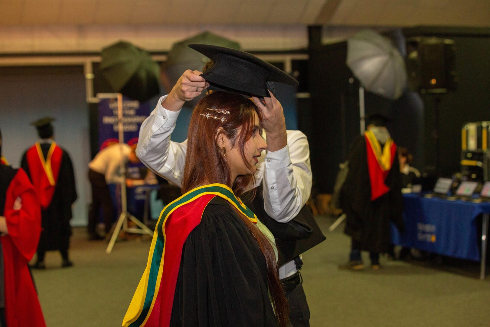a mortar board cap being placed on the head of a graduate