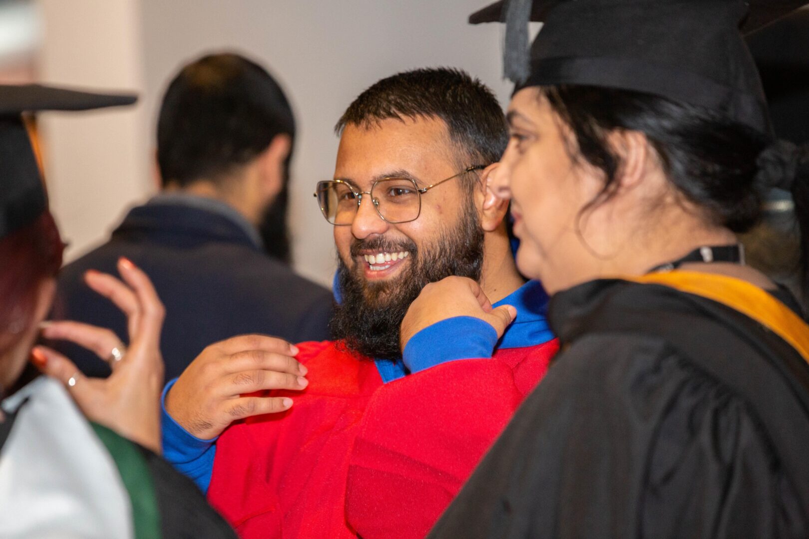 a smiling student laughs with his course tutors