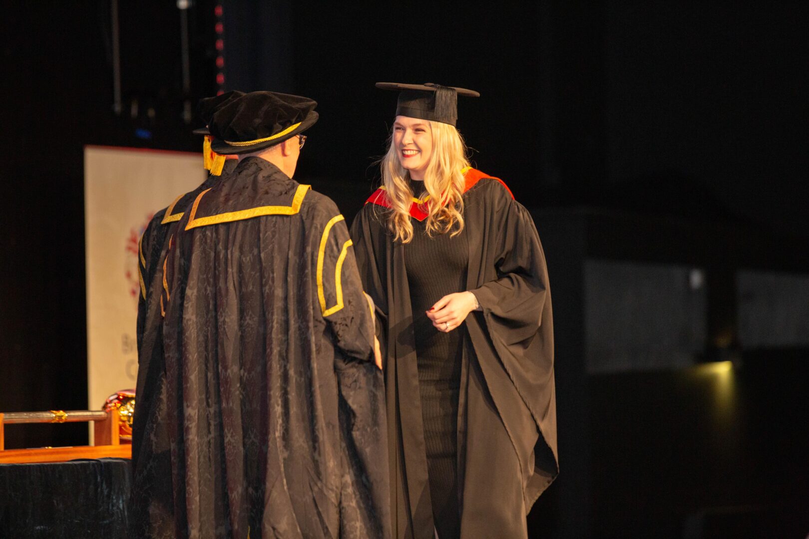 a smiling graduate as they shake hands on the stage
