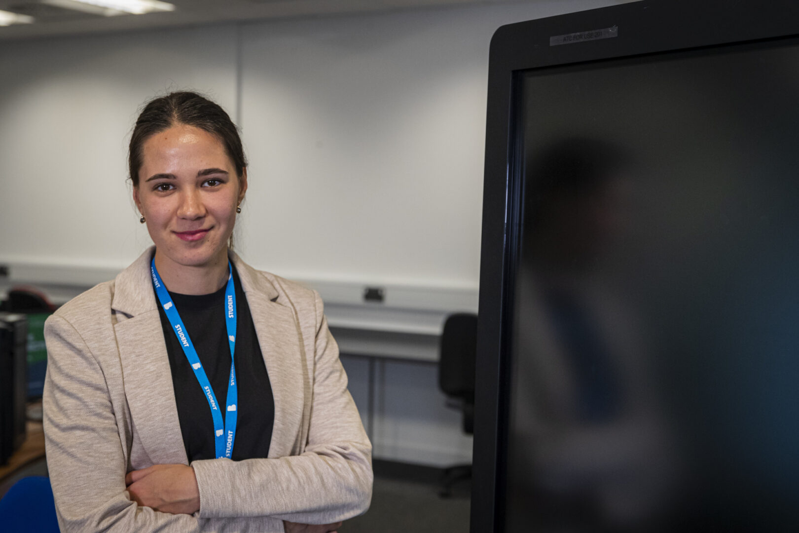 a computing student stands next to a monitor smiling