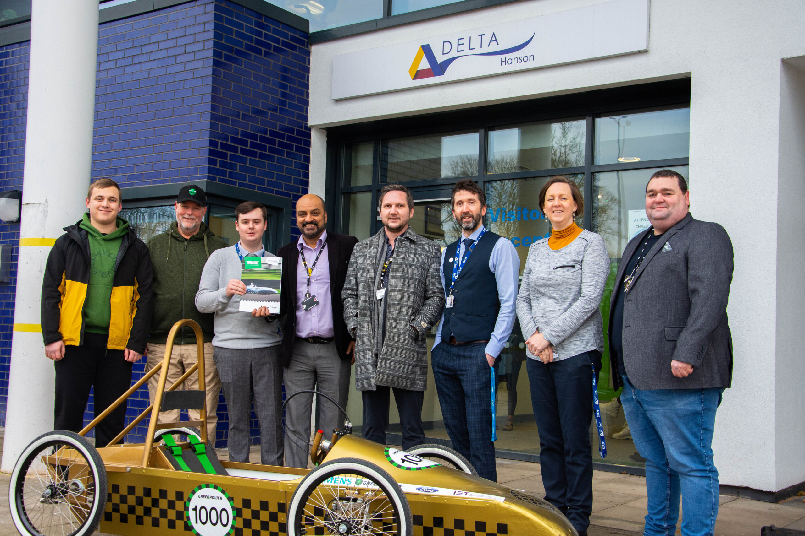 representatives from bradford college, greenpower and hanson school pictured outside of hanson school as they deliver a greenpower go kart to the school