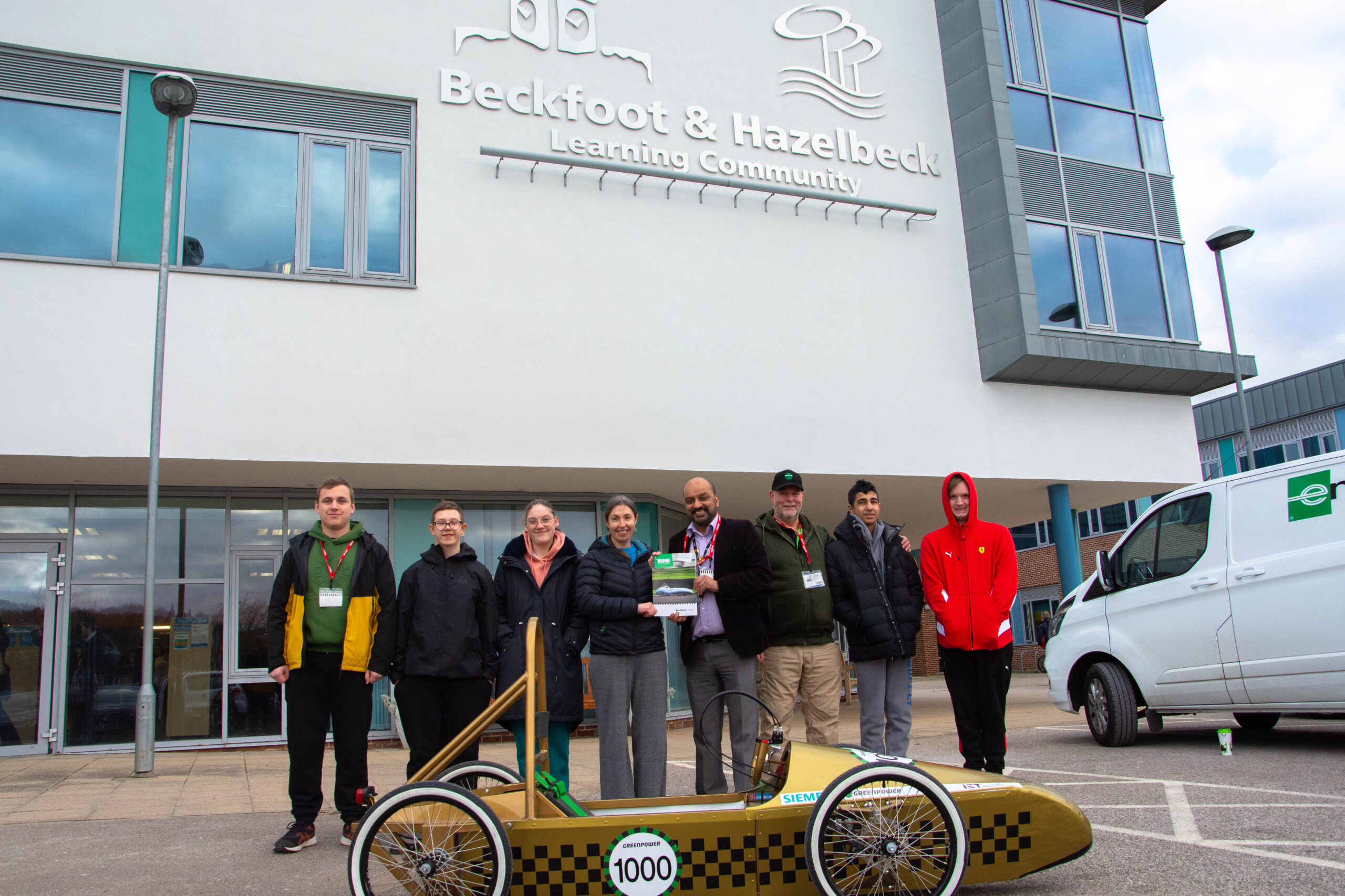 representatives from bradford college, greenpower and beckfoot and hazelbeck school pictured outside of beckfoot and hazelbeck school as they deliver a greenpower go kart to the school