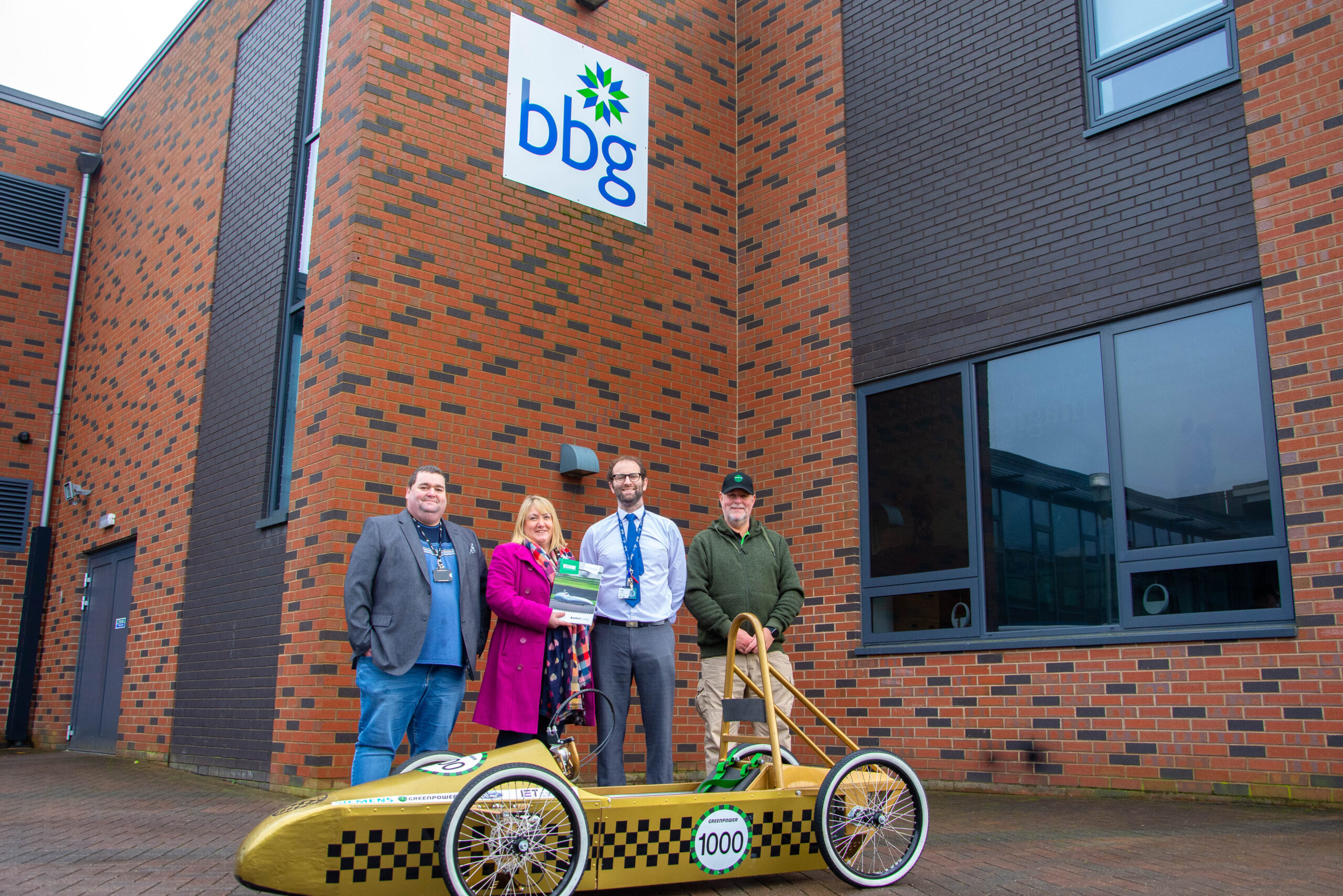 representatives from bradford college, greenpower and bbg school pictured outside of bbg school as they deliver a greenpower go kart to the school