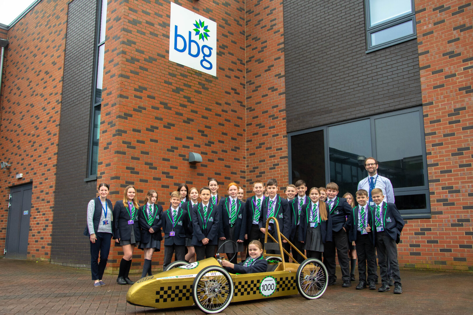 representatives from bradford college, greenpower and bbg school pictured outside of bbg school as they deliver a greenpower go kart to the school