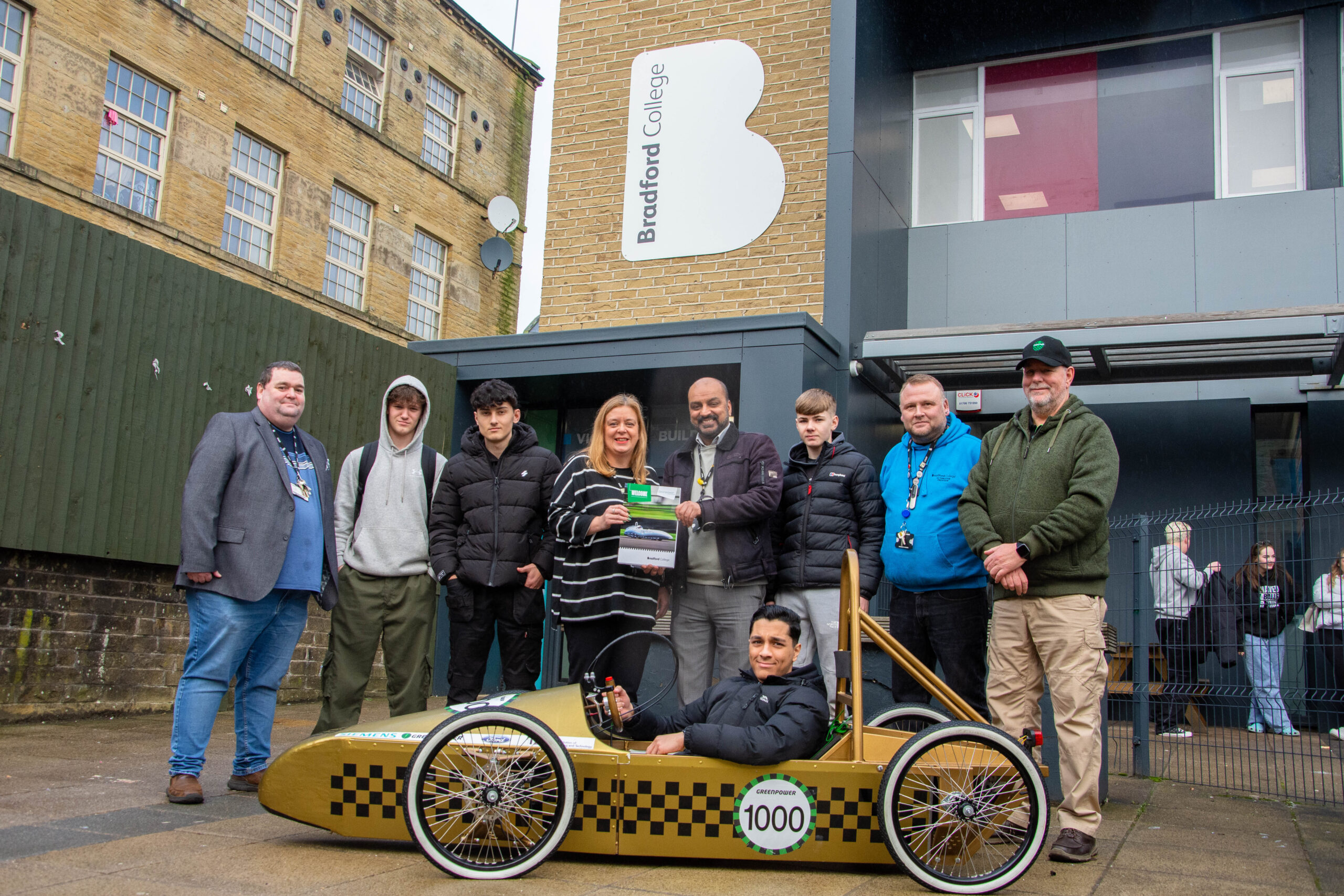 representatives from bradford college and greenpower pictured outside of the 14-16 victoria building as they deliver a greenpower go kart to the school