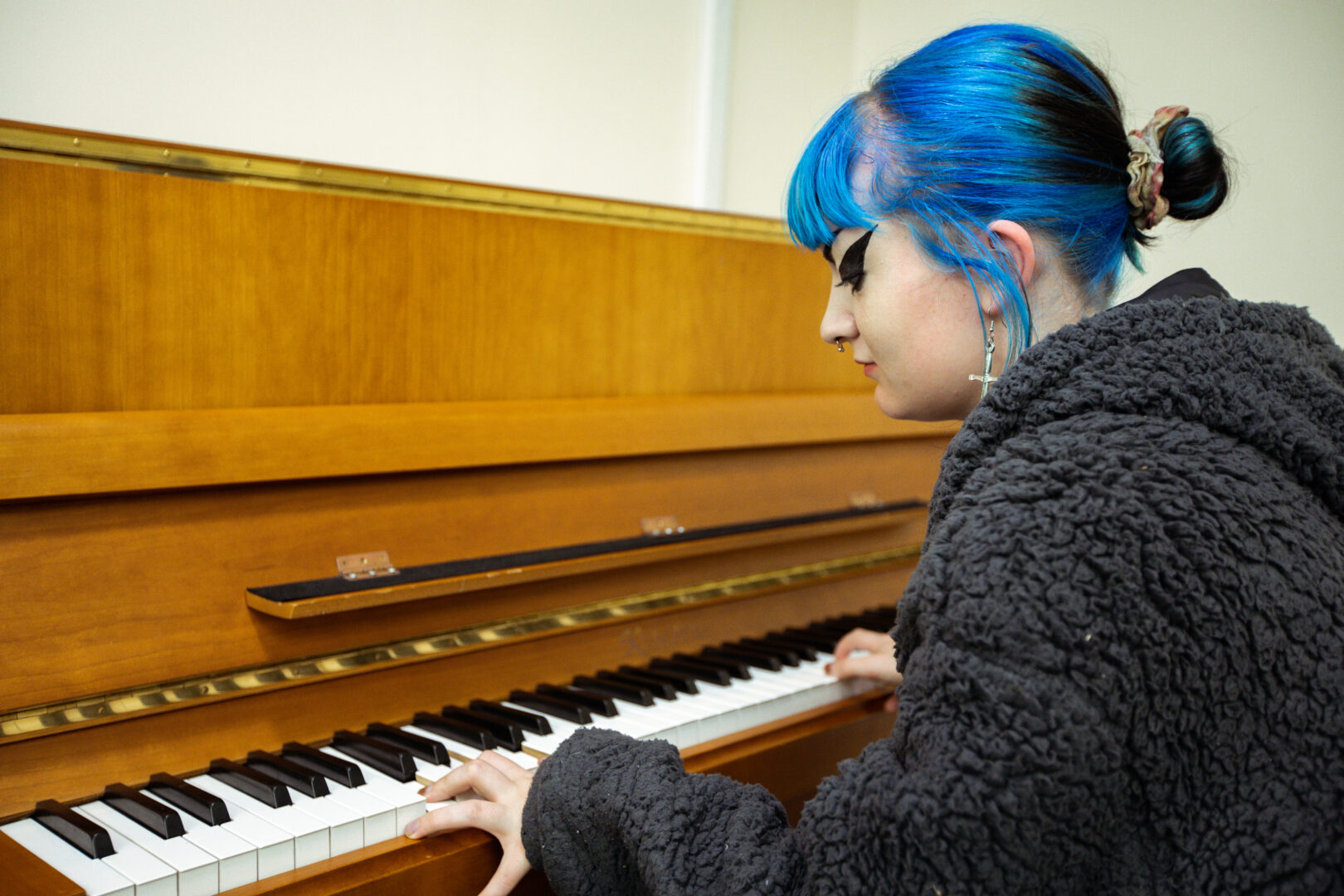a student sits at a piano and plays
