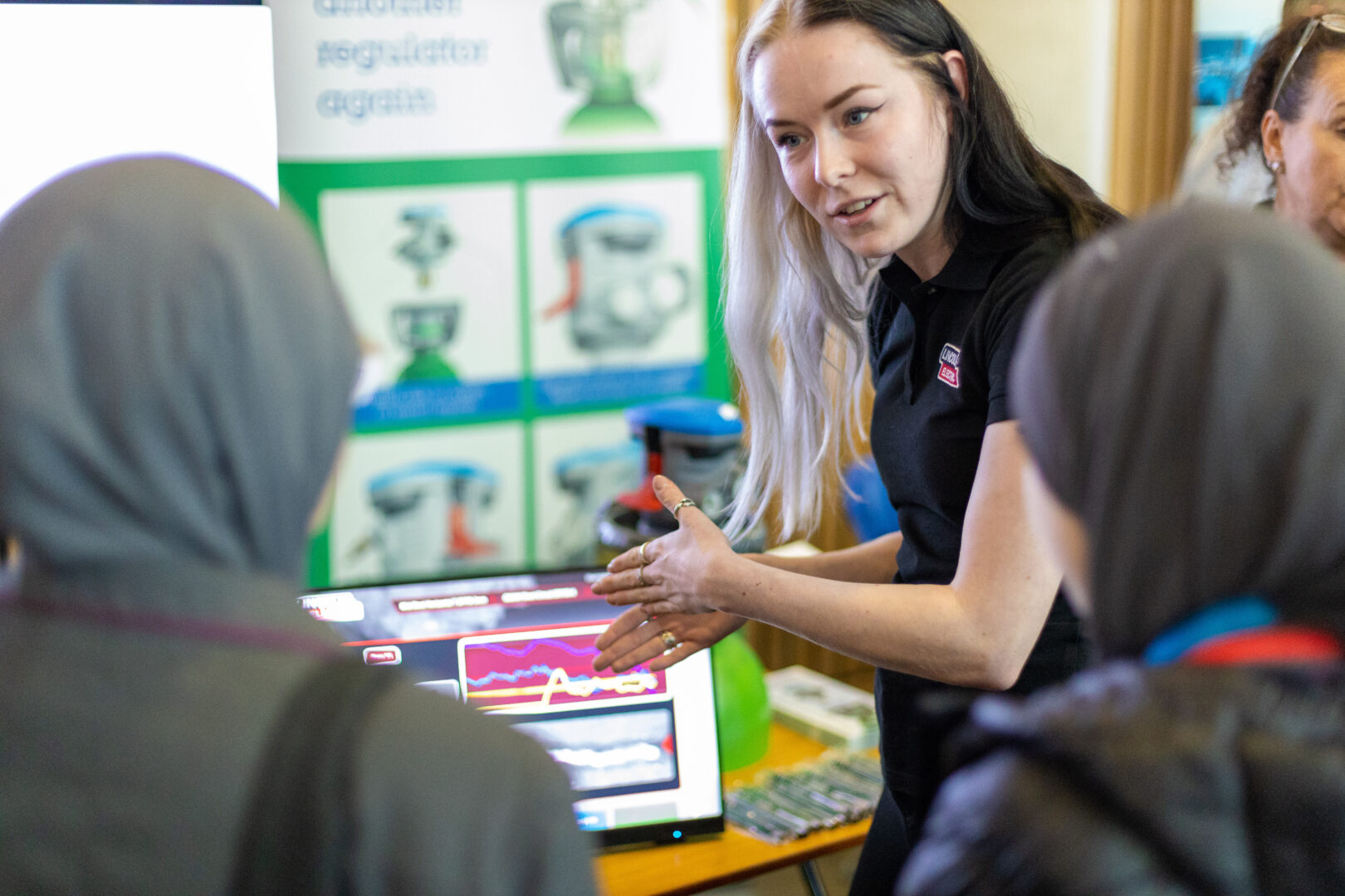 a woman stands speaking to a group of school students about the opportunities in stem