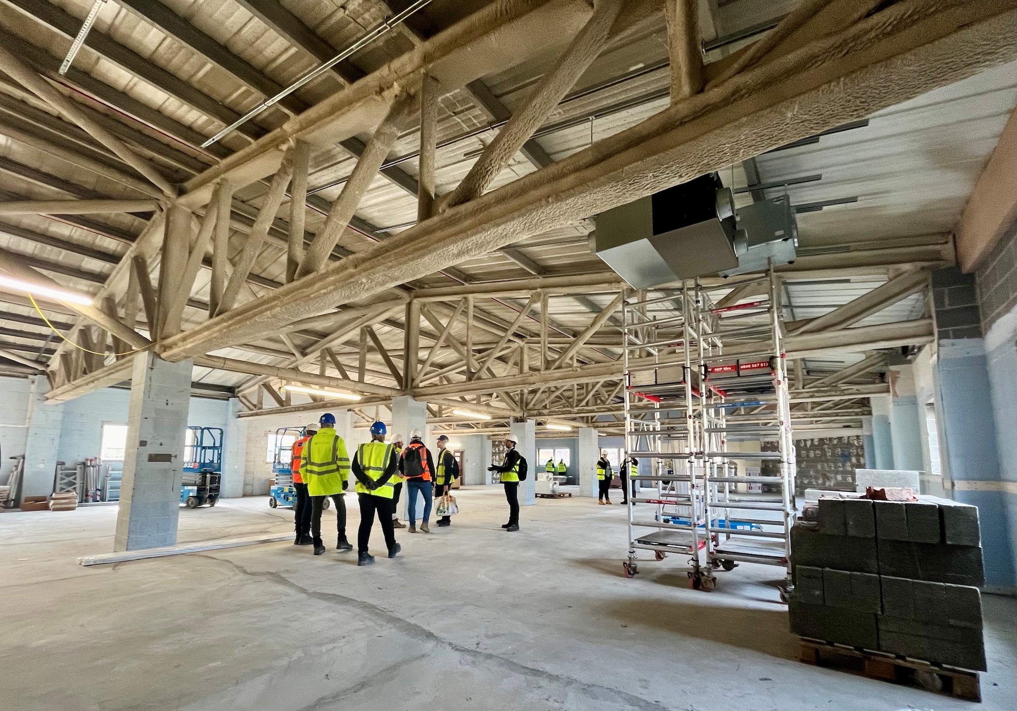 the inside of a building under construction with people wearing high vis jackets and hard hats in the background