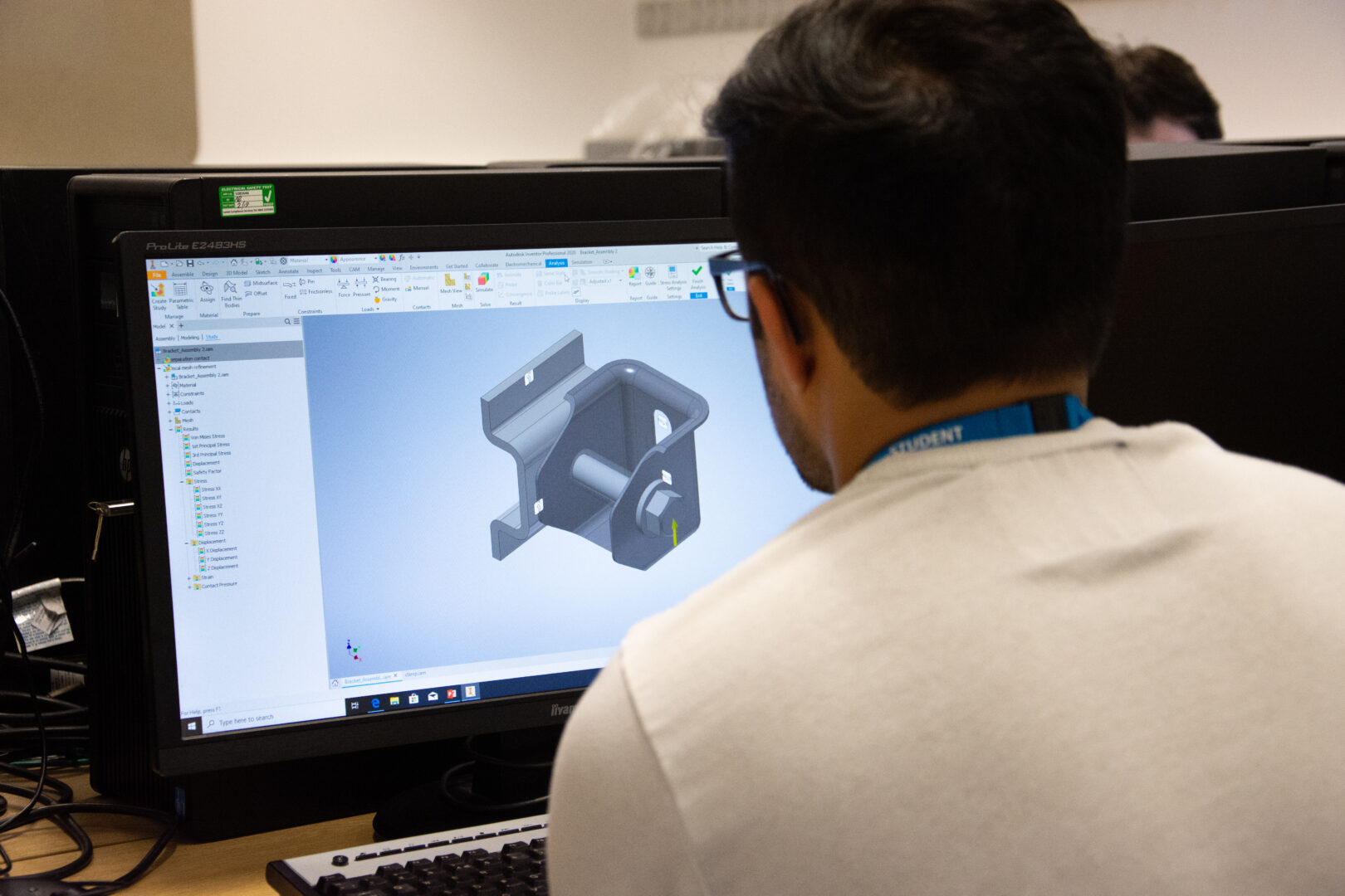 a student sits at a computer looking at a mechanical engineering project